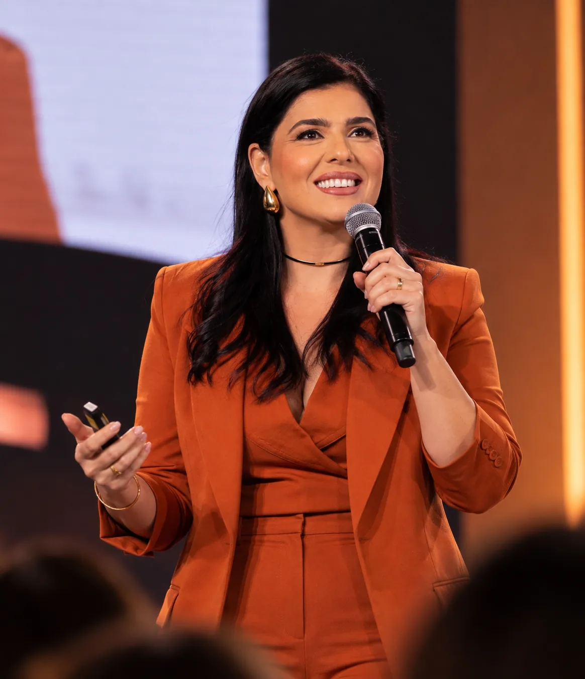 Tatiane Dib falando ao microfone em um palco